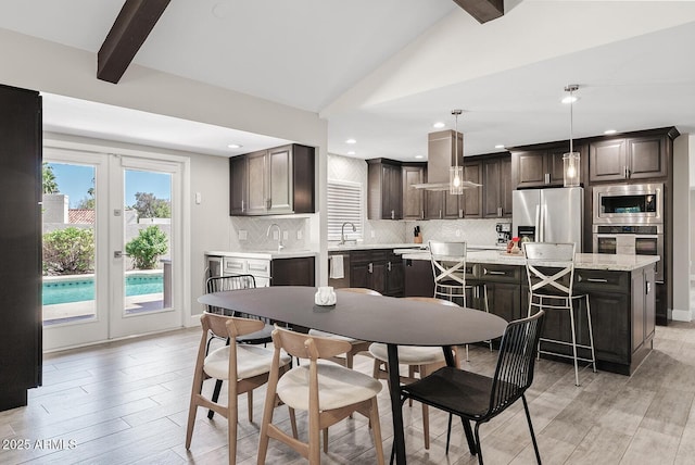 8361 E San Rafael Dr, Scottsdale, AZ 85258 - kitchen with stainless steel appliances, ventilation hood, dark brown cabinetry, light countertops, and backsplash