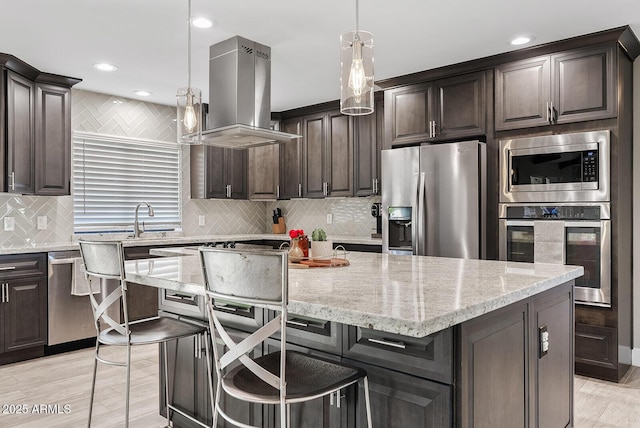 8361 E San Rafael Dr, Scottsdale, AZ 85258 - kitchen featuring stainless steel appliances, island exhaust hood, light stone counters, backsplash, and recessed lighting