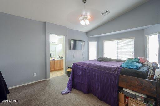 bedroom featuring carpet flooring, vaulted ceiling, ensuite bath, and ceiling fan