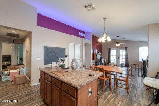 kitchen featuring pendant lighting, dark wood-type flooring, french doors, vaulted ceiling, and a kitchen island