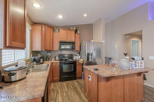 kitchen featuring a breakfast bar, sink, black appliances, hardwood / wood-style flooring, and a kitchen island