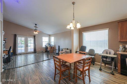 dining area featuring dark hardwood / wood-style floors, lofted ceiling, ceiling fan with notable chandelier, and french doors