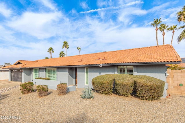 ranch-style house with concrete driveway, a tiled roof, an attached garage, and stucco siding