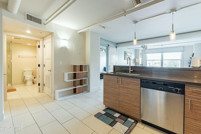 kitchen with pendant lighting, sink, light tile patterned floors, dishwasher, and a barn door