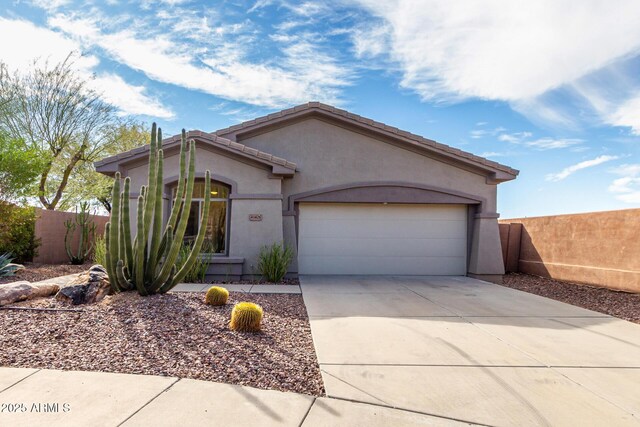 view of front of house featuring driveway, a garage, fence, and stucco siding