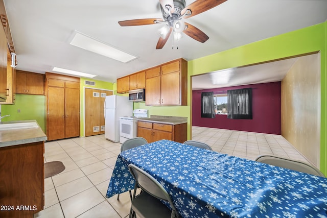 kitchen featuring light tile patterned flooring, white appliances, ceiling fan, and sink