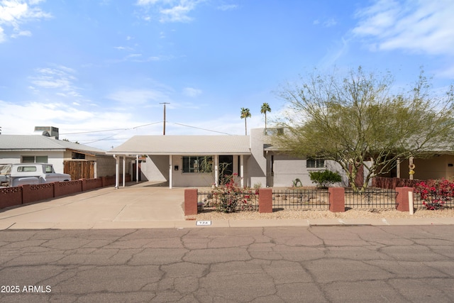 single story home with a carport, concrete driveway, and a fenced front yard