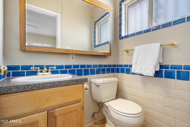 bathroom with tile walls, toilet, and vanity