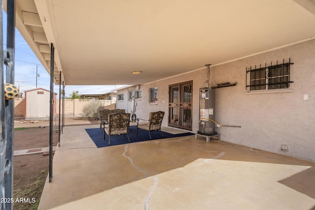 view of patio / terrace featuring a storage unit, an outdoor structure, water heater, and fence