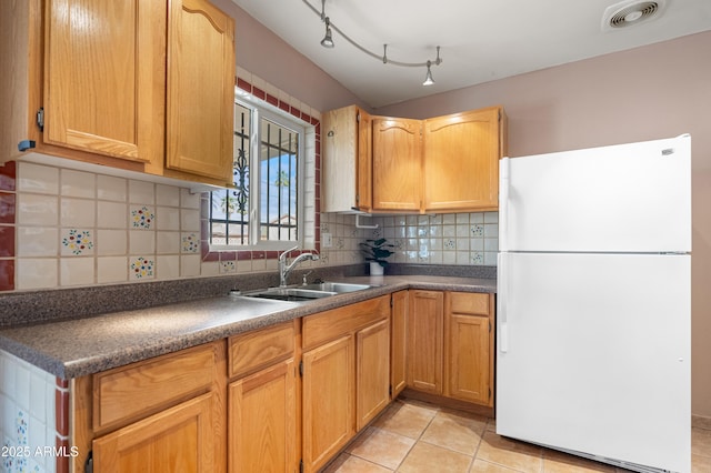 kitchen featuring dark countertops, visible vents, backsplash, freestanding refrigerator, and a sink