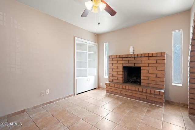 unfurnished living room with a brick fireplace, built in shelves, baseboards, light tile patterned floors, and a ceiling fan