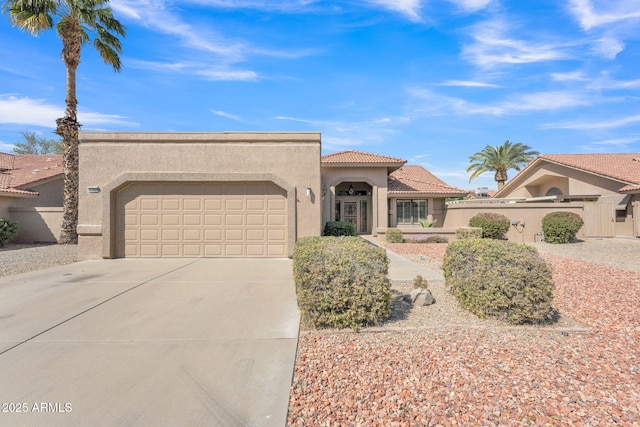 view of front of house with concrete driveway, a tile roof, an attached garage, and stucco siding