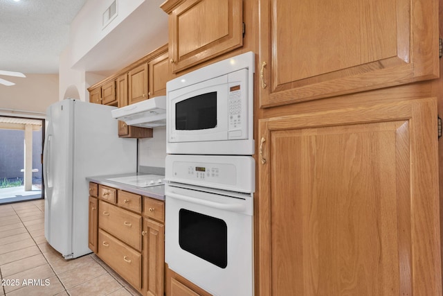 kitchen with light tile patterned floors, light countertops, visible vents, white appliances, and under cabinet range hood