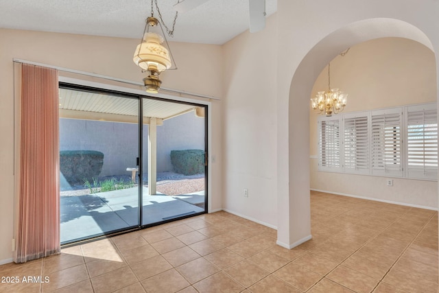 unfurnished room featuring arched walkways, a textured ceiling, a chandelier, baseboards, and tile patterned floors