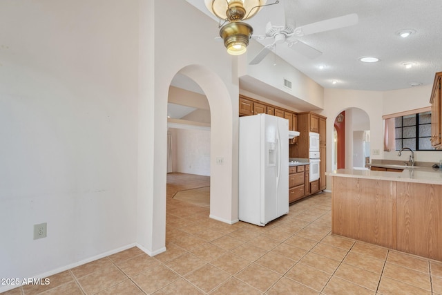 kitchen with arched walkways, white appliances, light tile patterned flooring, and visible vents