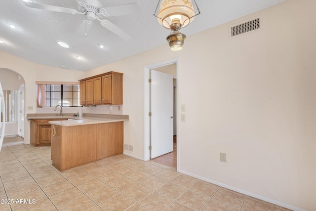 kitchen with a peninsula, visible vents, arched walkways, and light countertops