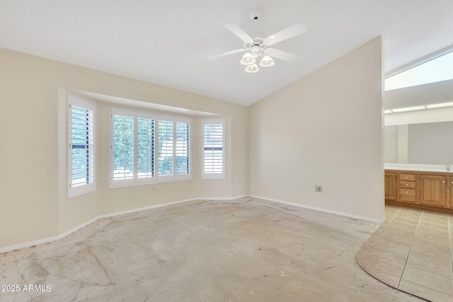 spare room with baseboards, vaulted ceiling, and a ceiling fan