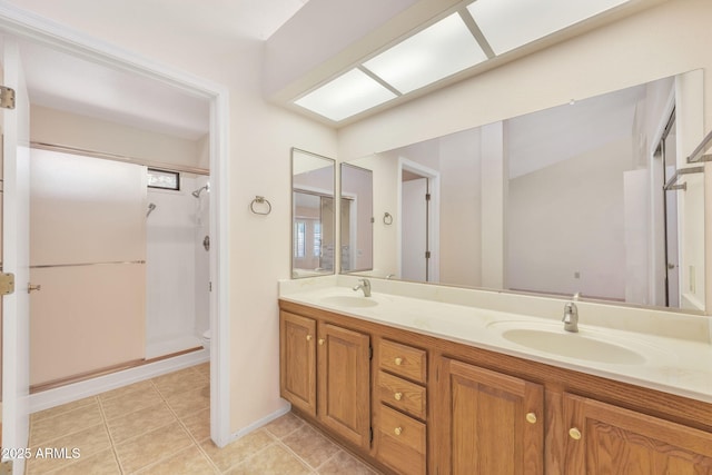 full bathroom with a shower, double vanity, a sink, and tile patterned floors