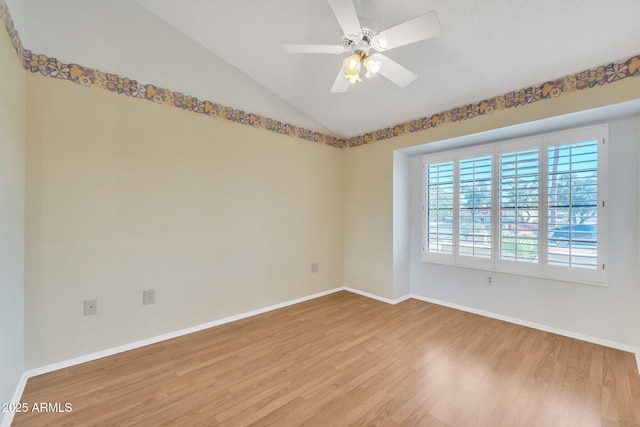 spare room with ceiling fan, vaulted ceiling, baseboards, and wood finished floors