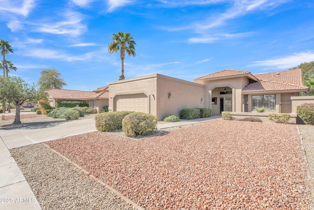 mediterranean / spanish-style home featuring a garage, concrete driveway, a tile roof, and stucco siding