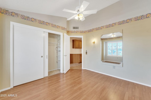 spare room featuring visible vents, light wood-style flooring, a ceiling fan, vaulted ceiling, and baseboards