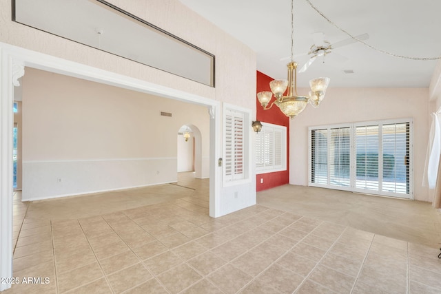 unfurnished room featuring light tile patterned floors, a chandelier, arched walkways, and light colored carpet