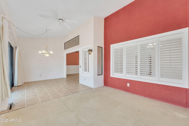 tiled spare room featuring ceiling fan with notable chandelier