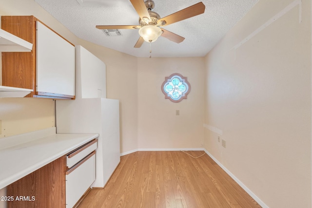 kitchen with visible vents, light countertops, light wood-style floors, white cabinetry, and a textured ceiling