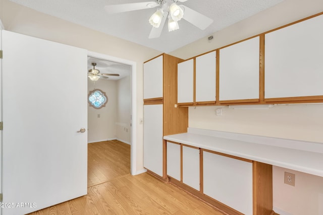 unfurnished room featuring light wood-style floors, ceiling fan, and a textured ceiling