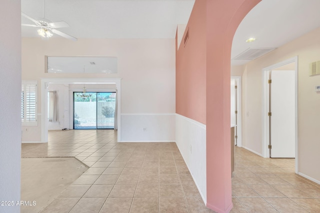 empty room featuring a ceiling fan, arched walkways, light tile patterned flooring, and visible vents