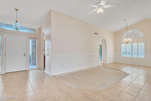 foyer featuring light tile patterned floors, visible vents, arched walkways, high vaulted ceiling, and ceiling fan with notable chandelier