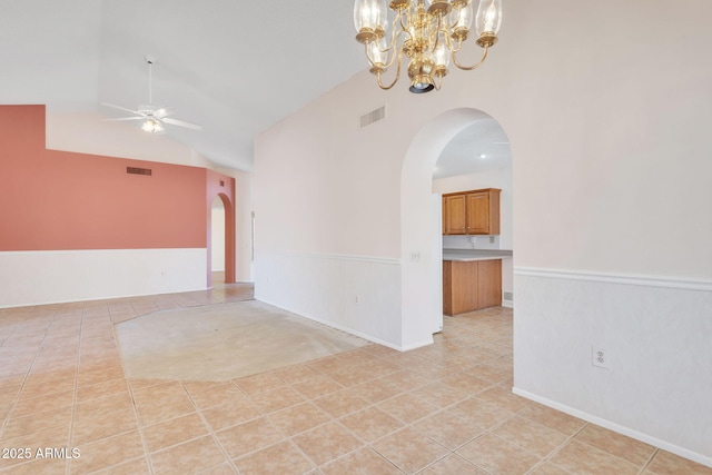 spare room with arched walkways, light tile patterned floors, wainscoting, and visible vents