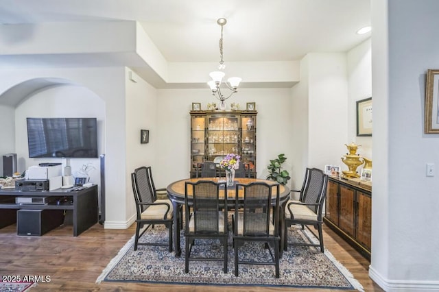 dining area with baseboards, wood finished floors, and a notable chandelier