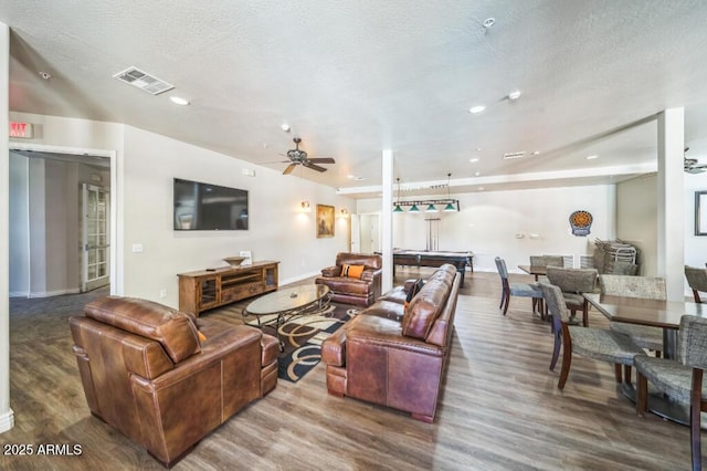 living room with a ceiling fan, a textured ceiling, visible vents, and wood finished floors
