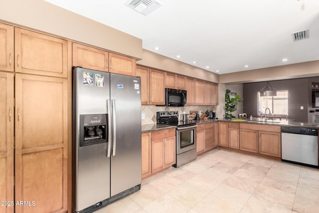 kitchen with stainless steel appliances, visible vents, a sink, and dark countertops