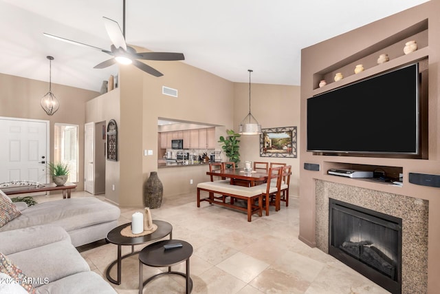 living room with a glass covered fireplace, visible vents, high vaulted ceiling, and ceiling fan