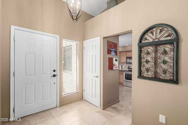 foyer with light tile patterned flooring, plenty of natural light, a high ceiling, and baseboards