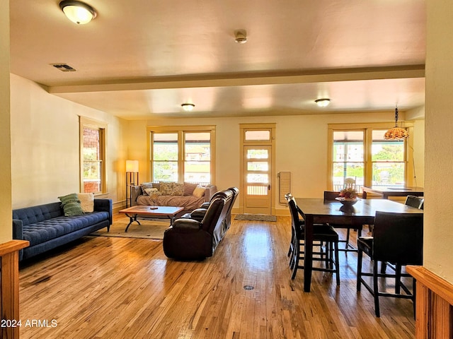 dining space featuring beam ceiling, a healthy amount of sunlight, and hardwood / wood-style floors