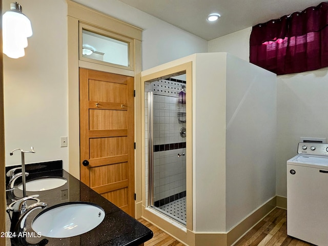 bathroom with hardwood / wood-style flooring, washer / dryer, dual vanity, and tiled shower