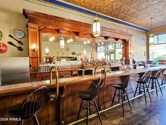 bar featuring plenty of natural light, crown molding, and hanging light fixtures