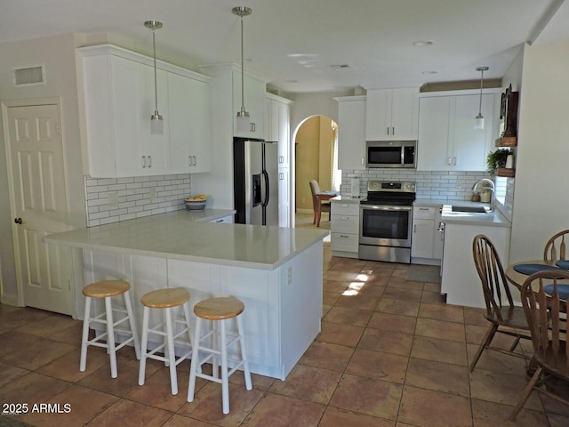 1010 N Osprey Ct, Gilbert, AZ 85234 - kitchen featuring backsplash, a peninsula, appliances with stainless steel finishes, and a sink