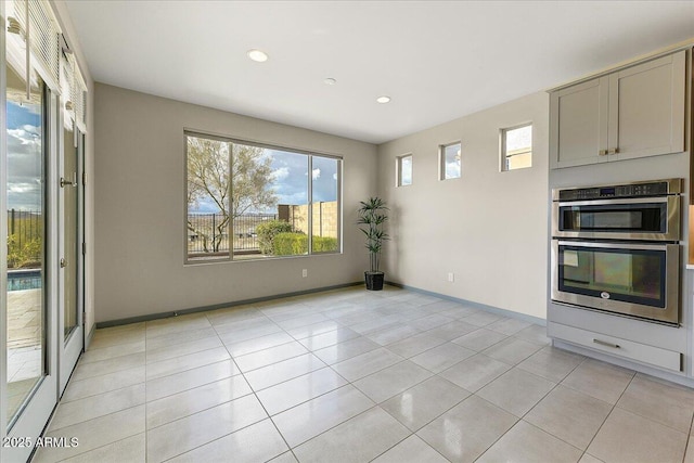 interior space featuring stainless steel double oven and light tile patterned floors