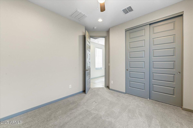 unfurnished bedroom featuring light carpet, ceiling fan, and a closet