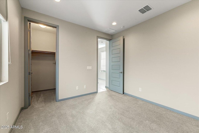 unfurnished bedroom with a spacious closet and light carpet