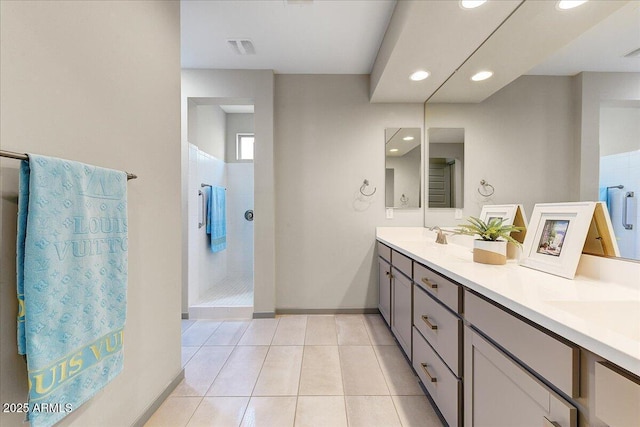 bathroom with tiled shower, vanity, and tile patterned floors