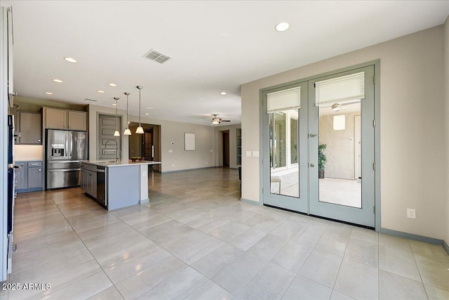 kitchen with appliances with stainless steel finishes, decorative light fixtures, ceiling fan, a center island with sink, and french doors