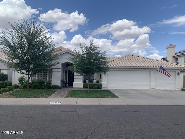 view of front of home featuring an attached garage, concrete driveway, a tile roof, stucco siding, and a front lawn
