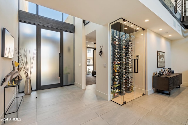 wine area with a high ceiling, light tile patterned floors, and a healthy amount of sunlight