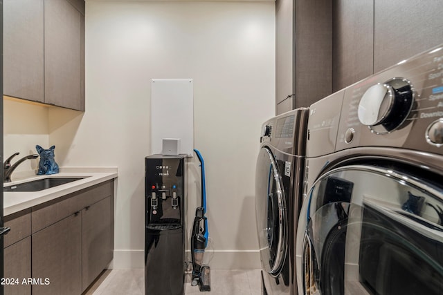 laundry area with light tile patterned flooring, sink, washing machine and clothes dryer, and cabinets