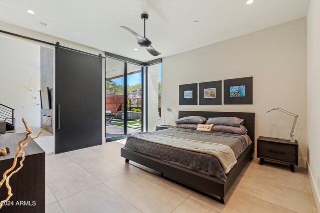 bedroom featuring access to outside, ceiling fan, light tile patterned floors, a wall of windows, and a barn door